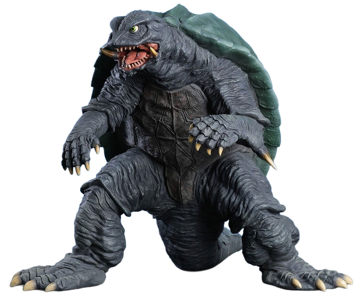 A detailed monster figurine of a reptilian kaiju with a dark gray textured body, green shell, and open mouth showing sharp teeth, isolated on a white background.