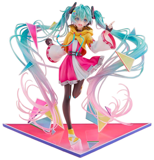 A stylized anime figurine of Hatsune Miku standing on a pink display base, with turquoise twin buns, a yellow and pink outfit, and flowing multicolored ribbon-like hair details against a plain white background.