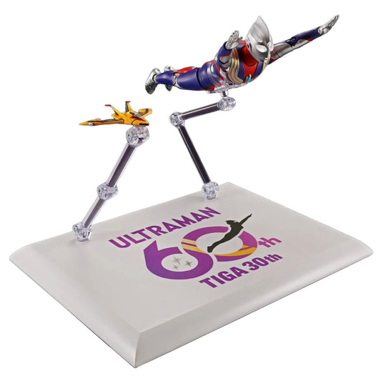 Ultraman 60th TIGA 30th commemorative display stand featuring a Ultraman figure posed above a small yellow fighter jet on clear articulated legs over a printed white base.