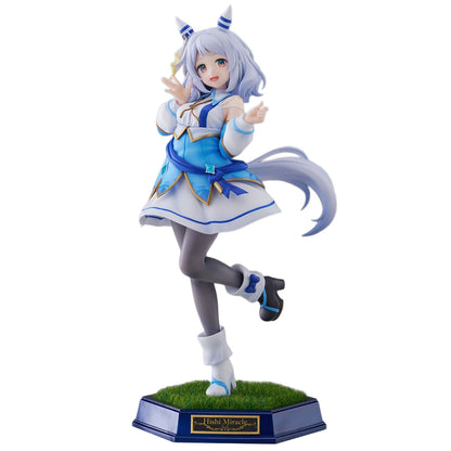 A collectible anime figurine of the character Hishi Miracle from Umamusume: Pretty Derby, posed mid-dance on a grassy base. The figure features light blue hair, a blue and white dress, gray tights, and black shoes, set against a plain white background.